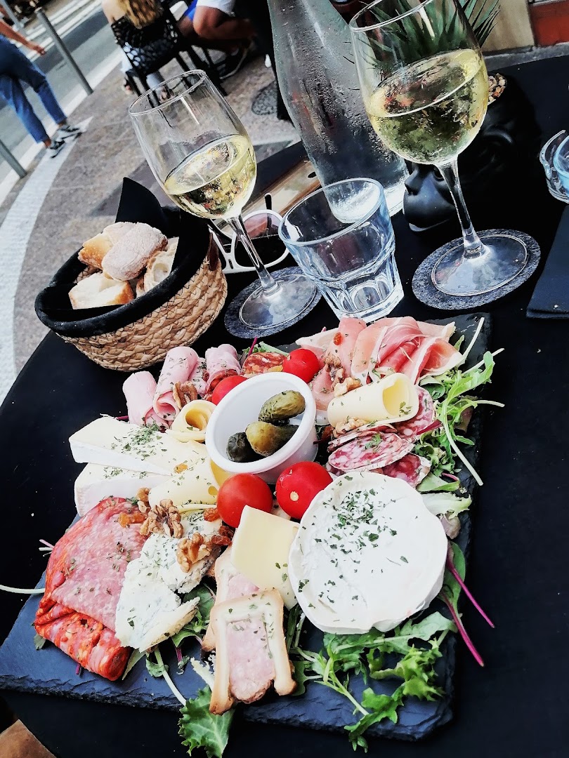 Une planche de charcuterie et fromage avec du pain et du vin blanc